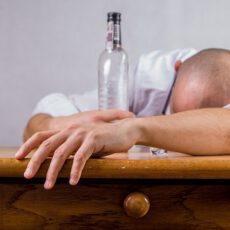 Leżący mężczyzna przy butelce po alkoholu