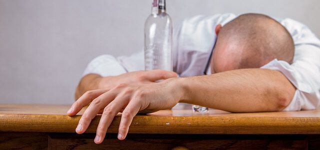Leżący mężczyzna przy butelce po alkoholu